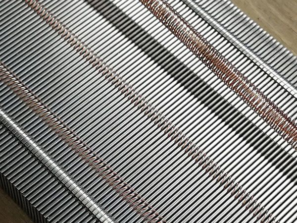 Schrägansicht eines Metallkamms mit parallel angeordneten Metallstäben und kupferfarbenen Bindedrähten