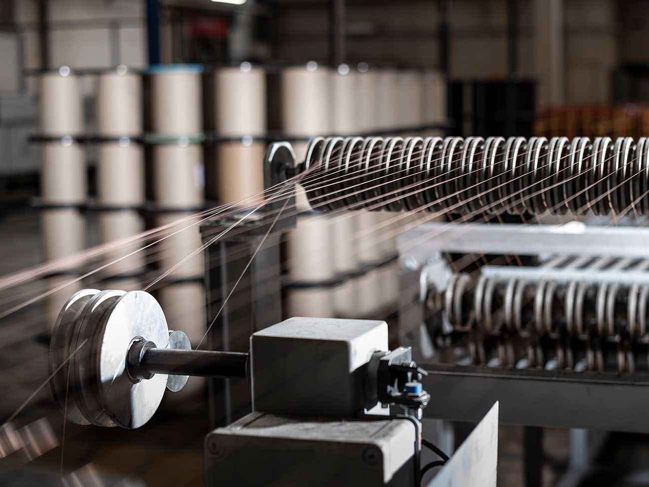 Luftaufnahme eines Industrieareals mit langgestreckten Produktionshallen, Bahnlinie und umliegenden Feldern.