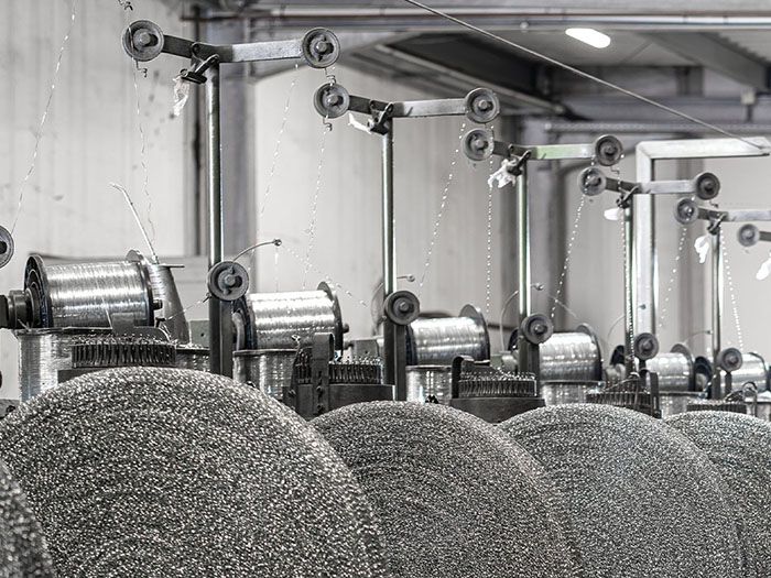 Reihe von zylindrischen Metallgestrickrollen auf einer industriellen Strick- und Produktionsanlage